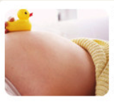 임산부의 배 부분 사진, 옆에 노란 오리 인형이 놓여 있음